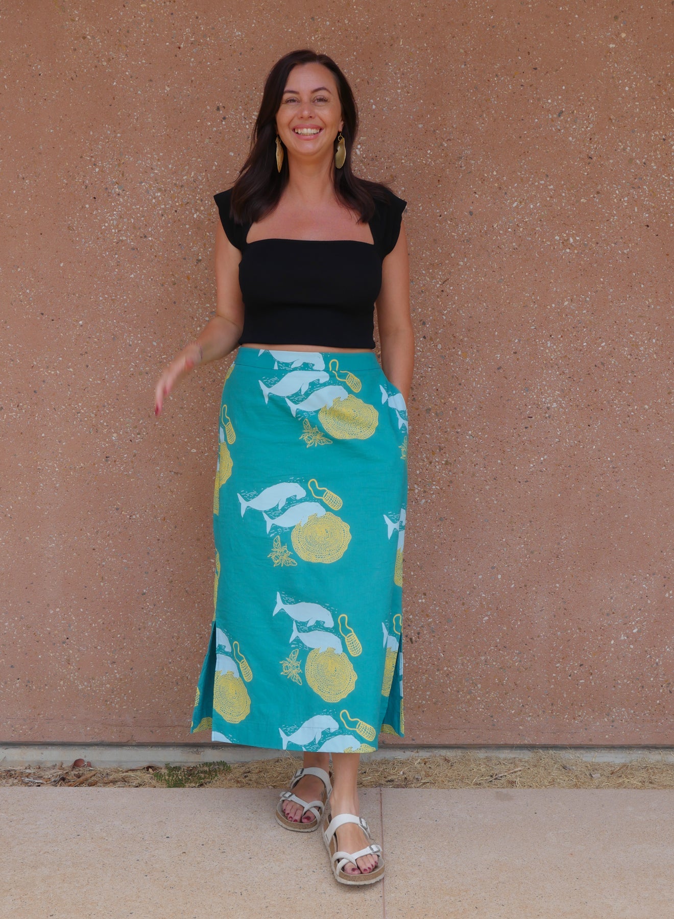 Woman wearing a teal skirt with animal pattern against a beige wall